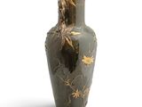 a black vase with gold leaves on it on a white background