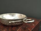an old silver bowl with a snake handle sitting on a red marble block