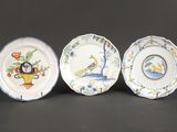 trois assiettes ornées d'oiseaux et de fleurs, posées sur une table