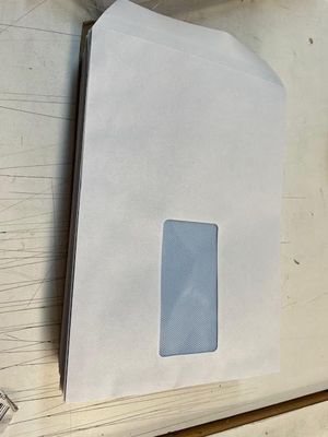 une enveloppe blanche avec une fenêtre, posée sur une table en bois