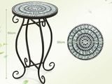 the table is made of metal and has a mosaic pattern on it
