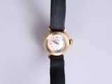 a gold watch with a black band on a white surface