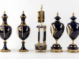 four vases and a clock sitting on a table