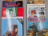 Plusieurs livres sont alignés sur une table devant un fond gris.