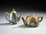 une paire de théières anciennes en argent posées sur une table devant un fond noir