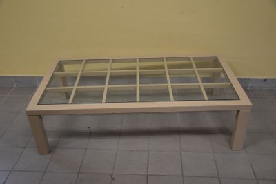 une table basse avec un plateau en verre posée sur un sol carrelé