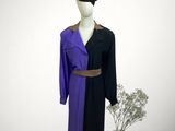 purple and black coat on a mannequin stand next to a vase of flowers