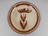 a brown and white plate with a flower design on it