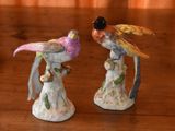 two figurines of birds sitting on a wooden table