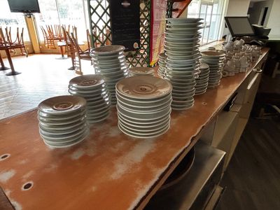 beaucoup d'assiettes empilées sur une table dans la cuisine