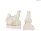 two white statues of animals on a white surface