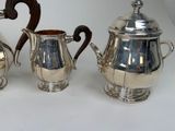 three pieces of silver tea and coffee set on a white surface