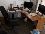 a desk with two computers and a chair in the corner