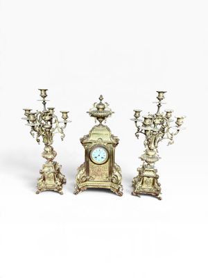 three silver candlesticks and a clock on a white background
