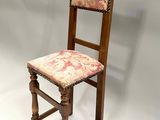 an old wooden chair with a floral upholstered seat on a white background
