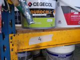 Plusieurs seaux de peinture sont empilés sur une étagère dans un garage