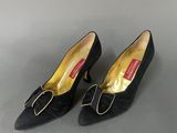 a pair of black shoes with a bow on the heel