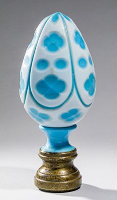vase en verre bleu et blanc, avec un socle doré sur fond blanc