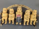 cinq figurines en bois représentant des personnes assises sur un banc