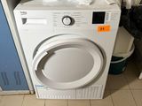 une machine à laver blanche posée sur une pile de vêtements