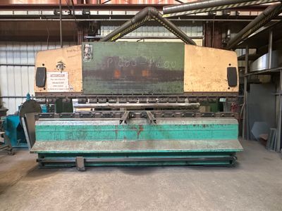 une photo d'une grande machine dans un entrepôt, sur laquelle est apposée une pancarte