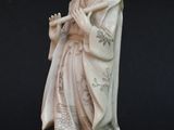 statue d'un homme tenant une flûte à la main, sur fond noir