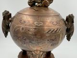an old bronze vase with a monkey sitting on top of it
