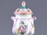 a pink and white vase with a lid on a clear stand