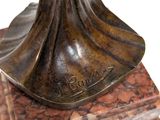 bronze statue of a woman holding a bird on a marble base