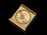 a gold clock that is sitting on a black surface
