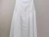a white dress hanging on a hanger against a wall