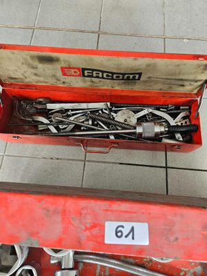 une boîte à outils rouge remplie d'outils, posée sur un sol carrelé