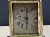 a small gold clock with roman numerals on it