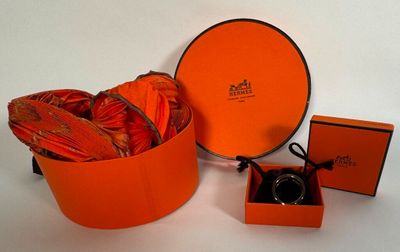 une boîte orange contenant une bague, posée à côté d'une paire de chaussures orange