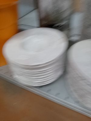 Plusieurs assiettes blanches sont empilées sur un plateau dans une cuisine.