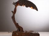 une sculpture en bronze représentant un oiseau perché sur une branche d'arbre