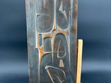 une sculpture en bronze représentant une femme assise sur un chevalet en bois