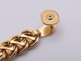 an image of a gold bracelet with a chain on a white surface