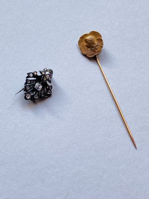 une photo représentant une épingle et une broche en forme de fleur posées sur une surface blanche