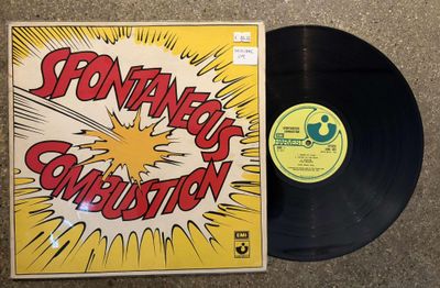 a black vinyl record sitting on top of a table next to a yellow and red cover