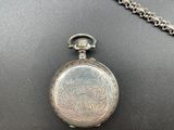 a close up of a silver pocket watch on a chain