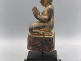 a statue of a person sitting on top of a wooden block