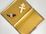 a small metal box with a cross and a pin on it