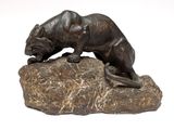 bronze statue of a panther on a rock on a white background