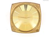 une horloge en or posée sur une surface blanche