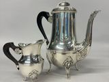 a silver plated tea set with two cups and a saucer