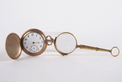 a gold pocket watch with a magnifying glass on it