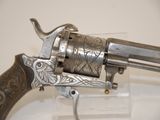an old revolver with a silver finish on a clear stand