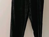 un pantalon en velours noir suspendu à un cintre devant un mur blanc