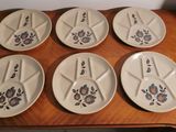 six white plates with blue flowers on them sit on a wooden table